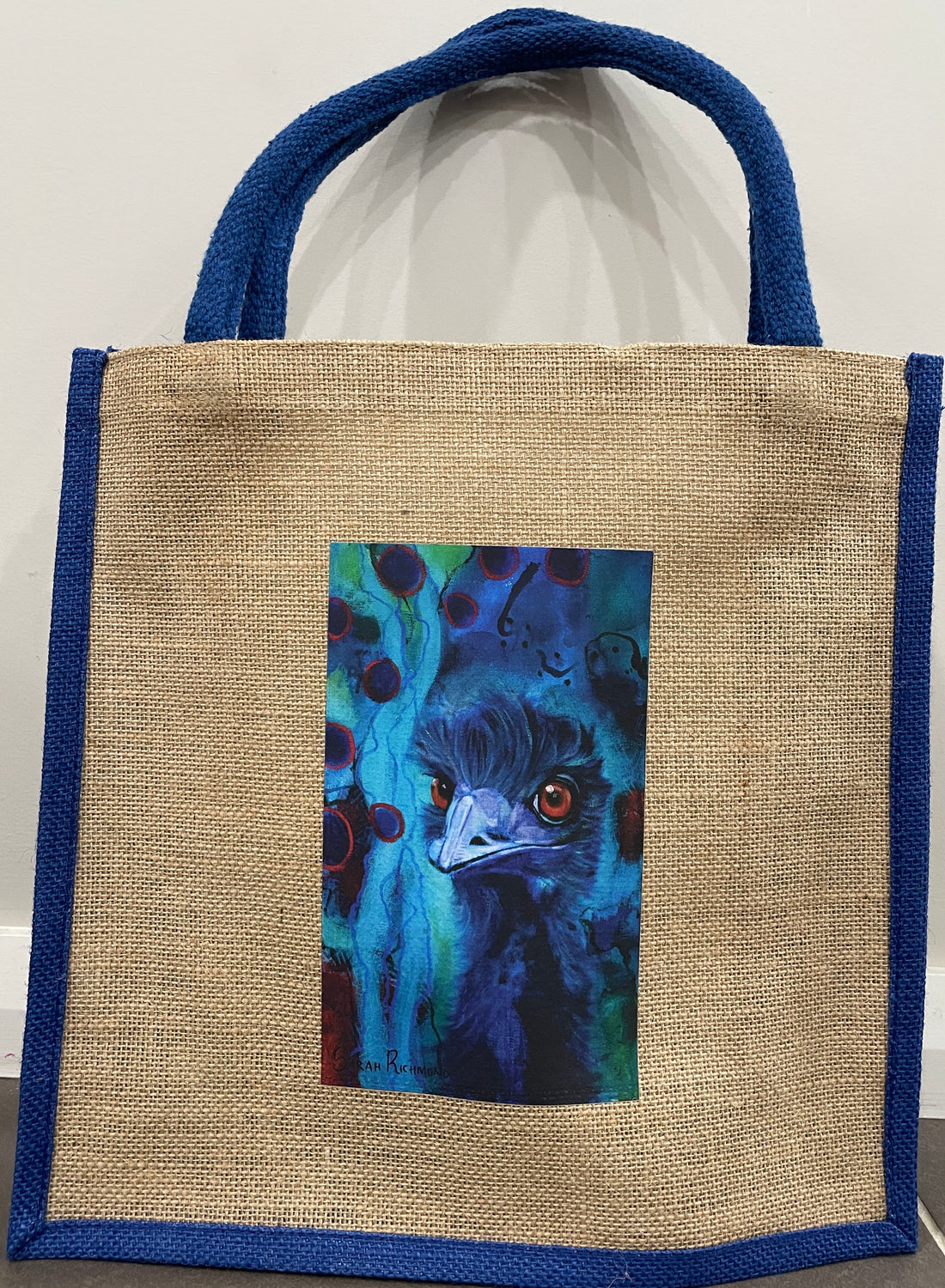 Jute tote bag with blue handles and trim with print of abstract realism emu with abstract background.
